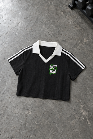 Squeeze & Hold cropped jersey – black cropped jersey with white collar and shoulder stripes, flat lay, AI-generated mockup